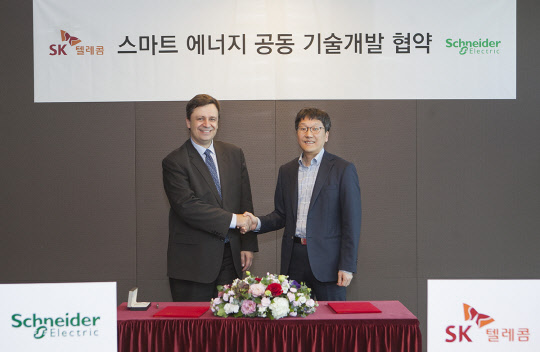 SK텔레콤이 슈나이더일렉트릭과 함께 인공지능을 이용한 건물 에너지관리에 나선다. 장홍성 SK텔레콤 솔루션기술원장(오른쪽)과 뤽 르몽 슈나이더일렉트릭 글로벌 부회장이 협약식 후 기념촬영을 하고 있다.  SK텔레콤 제공